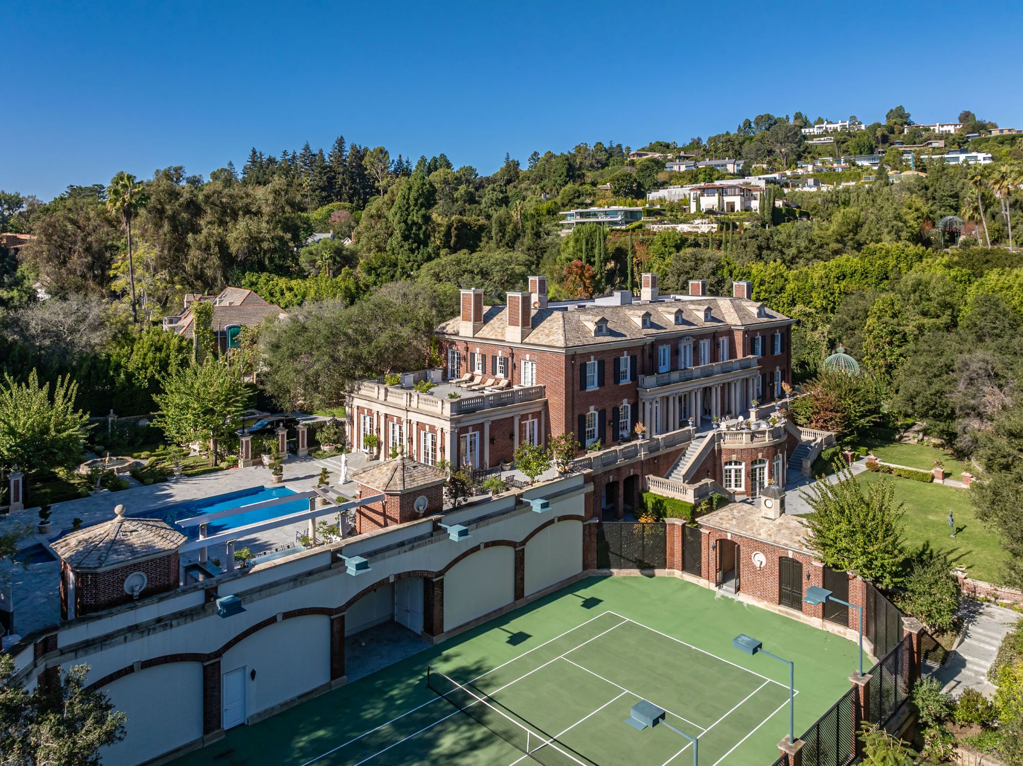 Luxurious Rosewood Estate surrounded by lush greenery, featuring a grand mansion, swimming pool, and tennis court.