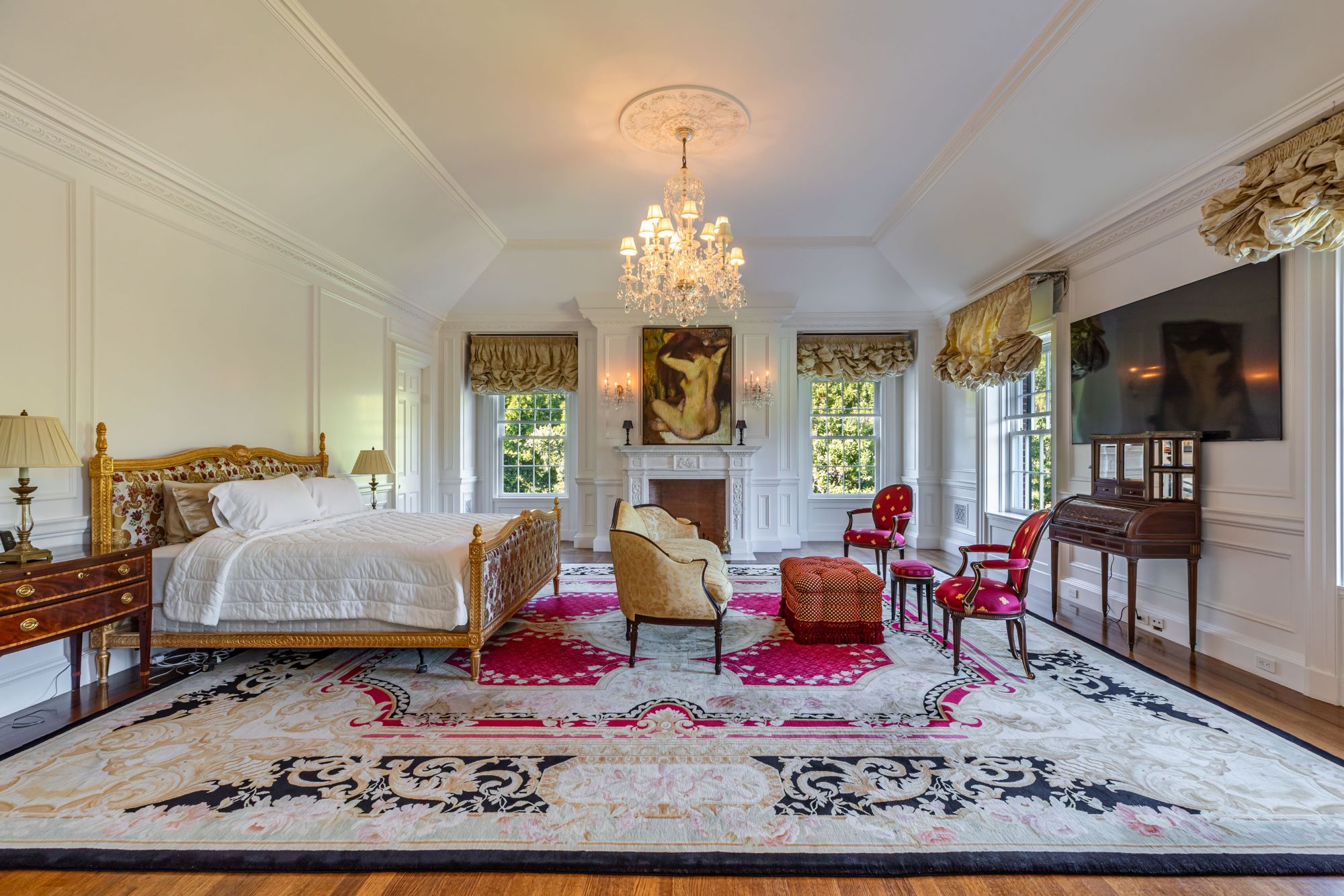 Luxurious bedroom featuring a gold-accented bed, elegant seating, and a chandelier, set in a refined decor at the Rosewood Estate.
